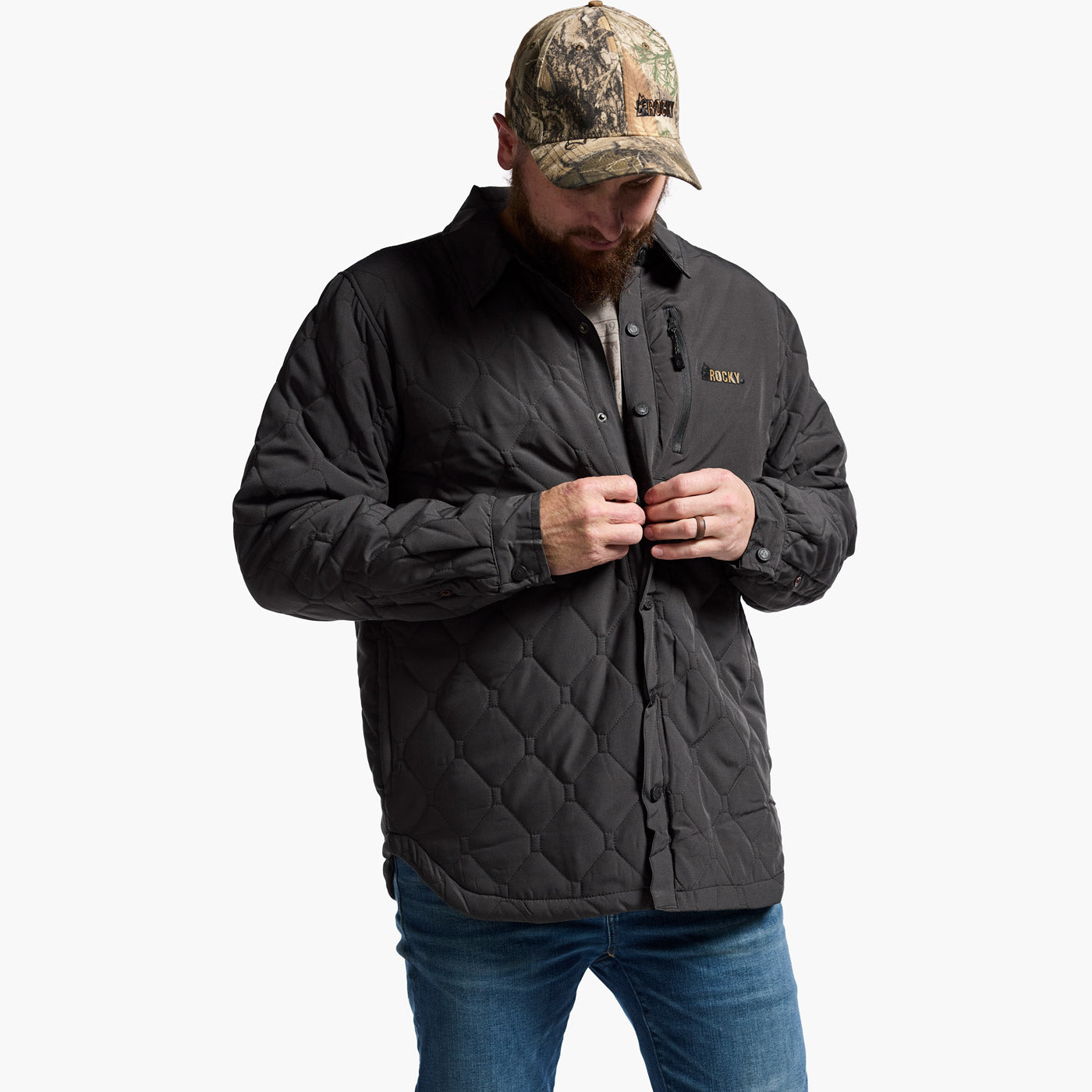 Man wearing a black quilted jacket and camouflage cap on a white background